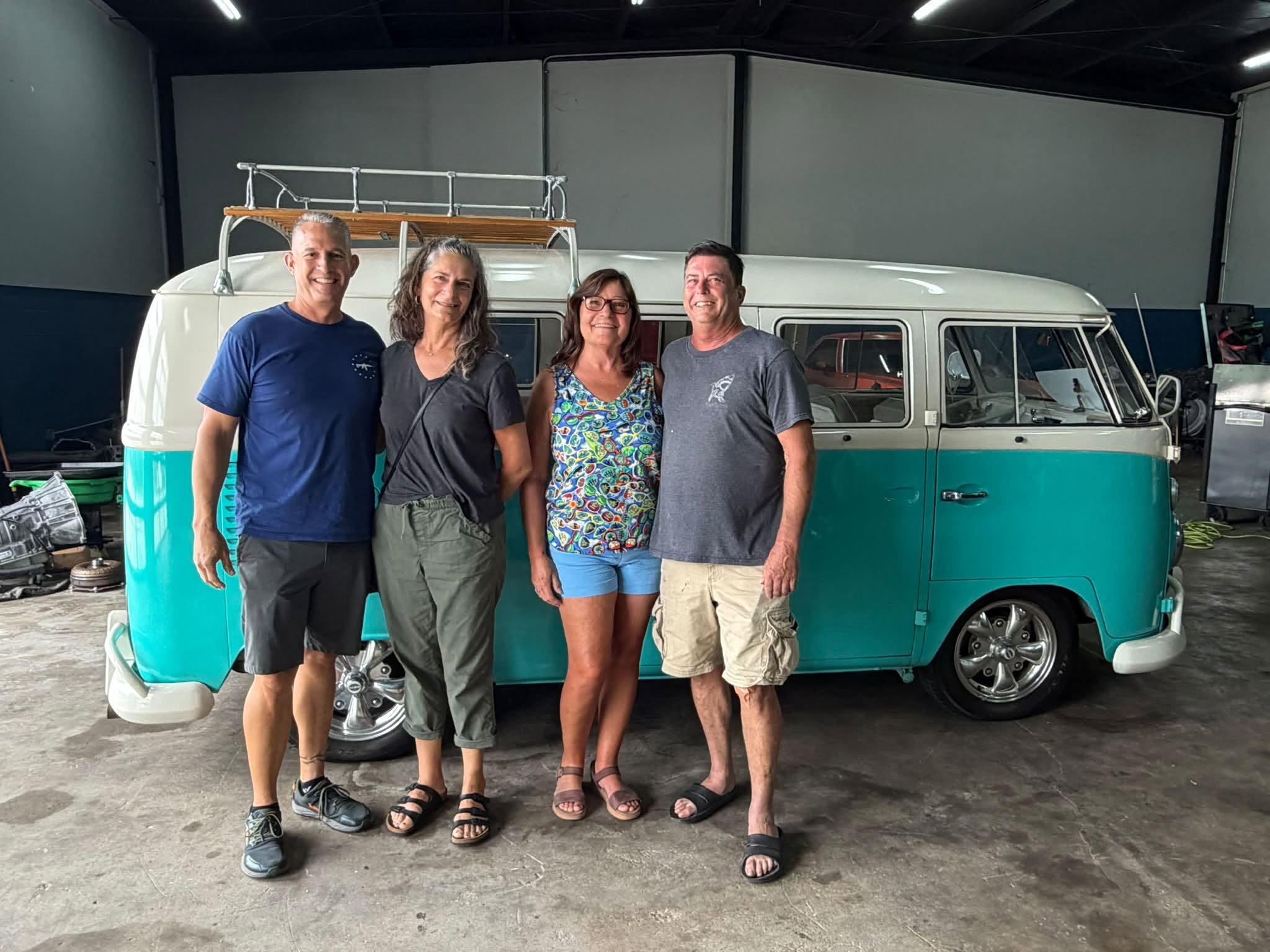 Car enthusiasts gathered beside a vintage Volkswagen bus at Tacot Garage